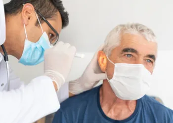 Doctor examining elderly man's ear for infection