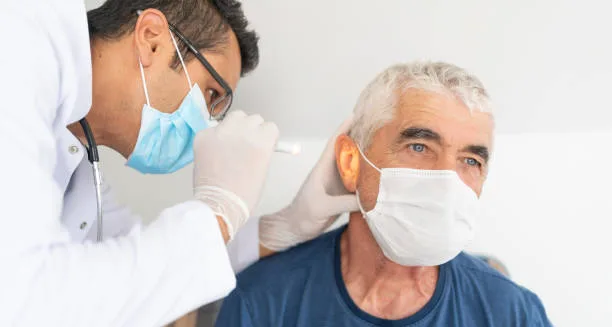 Doctor examining elderly man's ear for infection