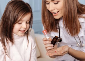 Female doctor showing medication to a young girl for early puberty treatment