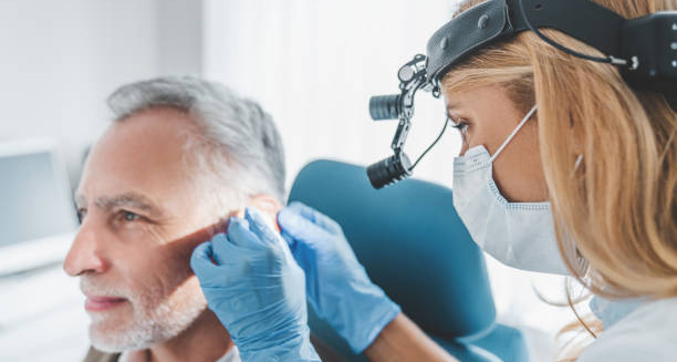 Medical professional treating earwax build-up in an older male patient