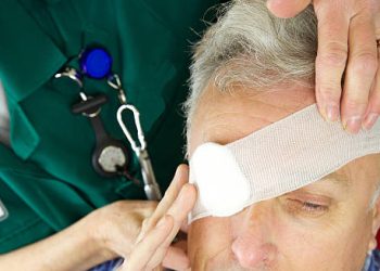 Medical professional applying bandage to injured man's eye