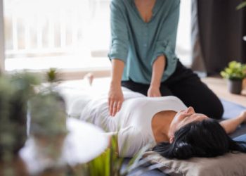 Woman lying on a mat receiving gentle therapeutic care, representing holistic treatment for a cracked rib.