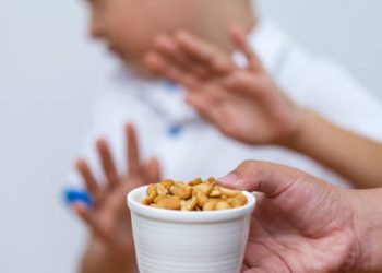 Child rejecting a bowl of peanuts, indicating an allergic or sensitivity reaction to food additives