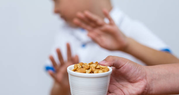 Child rejecting a bowl of peanuts, indicating an allergic or sensitivity reaction to food additives