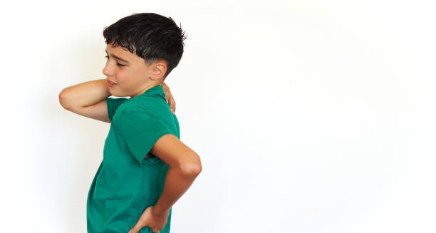 Boy showing signs of growing pains by holding his back and shoulder