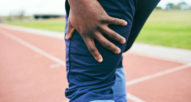 Athlete holding the back of his thigh in pain after a hamstring strain on the track