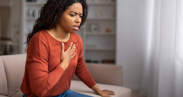 Woman holding her chest and gasping for air, showing early signs of heart failure