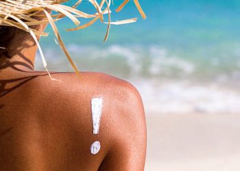 Exclamation mark drawn with sunscreen on sun-exposed shoulder warning of heat rash risks