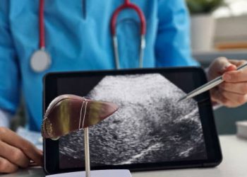 Doctor pointing at liver ultrasound scan to explain causes of hepatitis
