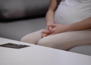 Pregnant woman sitting with ultrasound scan showing concern about hydrocephalus