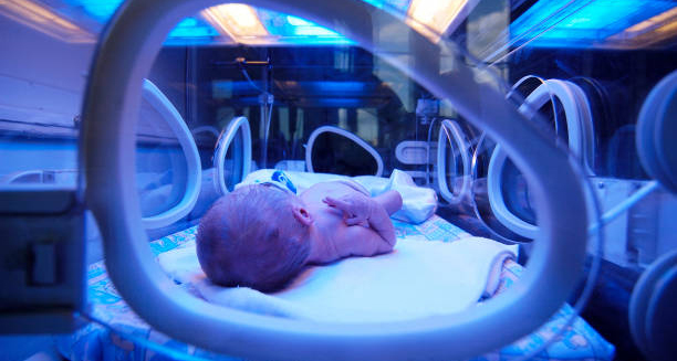 Newborn baby lying in an incubator, viewed through a window, symbolising complications of flat head syndrome