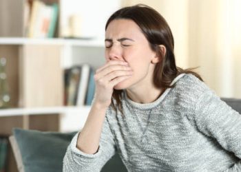 Woman covering mouth while experiencing nausea, possibly due to food intolerance