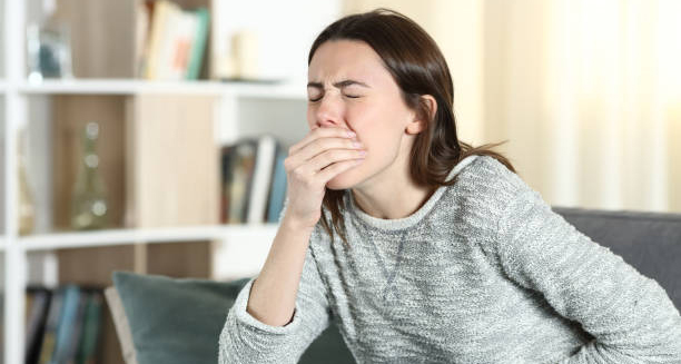 Woman covering mouth while experiencing nausea, possibly due to food intolerance