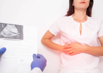 Woman holding her side with ultrasound scan result in doctor’s hand