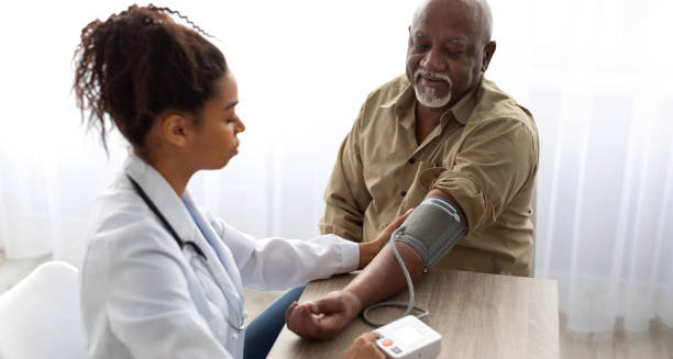 Doctor checking an elderly man's blood pressure, monitoring for heart disease complications