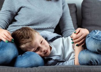 Unwell child lying on mother’s lap, illustrating complications of Hirschsprung’s disease