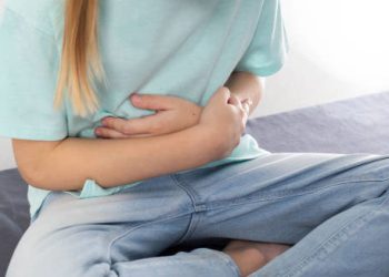 Child clutching stomach due to abdominal pain caused by hookworm complications