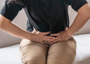 Woman clutching lower abdomen in pain due to complications from irritable bowel syndrome