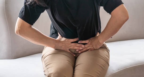 Woman clutching lower abdomen in pain due to complications from irritable bowel syndrome