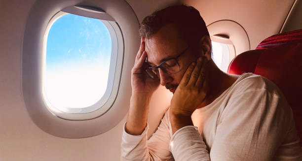 Man experiencing exhaustion and discomfort on an airplane, showing complications of jet lag