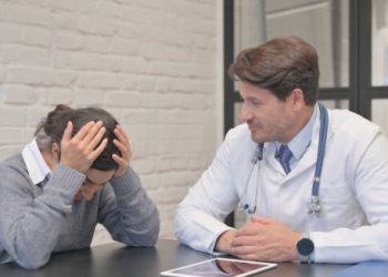 Female patient with head in hands during consultation with male doctor