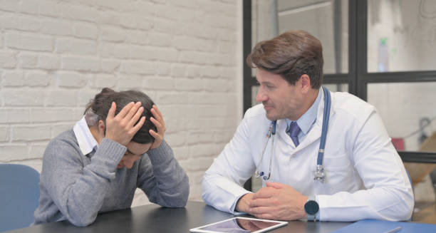 Female patient with head in hands during consultation with male doctor