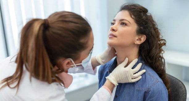 Doctor examining woman’s neck for glandular fever diagnosis