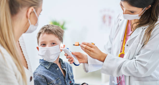 Doctor examining young boy's ear for signs of glue ear during a clinical assessment
