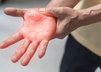 Elderly person experiencing numbness in the hand, a symptom used in Guillain-Barré syndrome diagnosis