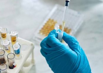 Gloved hand handling blood samples during hepatitis diagnosis