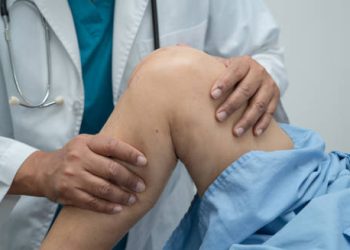 Doctor examining patient's leg for neuromuscular symptoms linked to hereditary spastic paraplegia