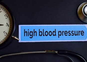 High blood pressure concept with clock and stethoscope on black background
