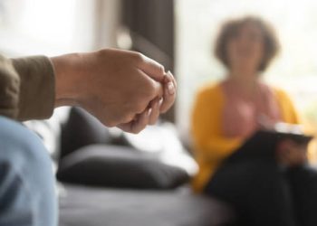 Person nervously clenching hands during a therapy session for hoarding disorder diagnosis