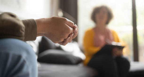 Person nervously clenching hands during a therapy session for hoarding disorder diagnosis