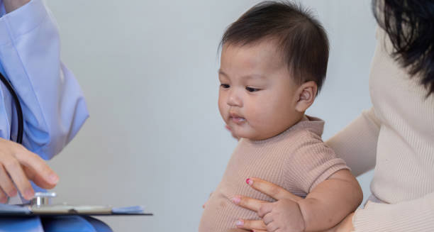 Doctor examining an infant for signs of hydrocephalus during a medical consultation.