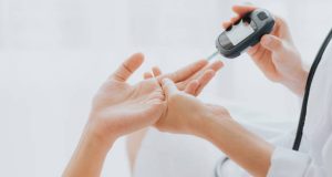 Blood glucose test being administered by a healthcare professional using a glucometer.