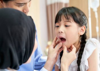 Paediatric doctor examining young girl's mouth and skin for impetigo symptoms