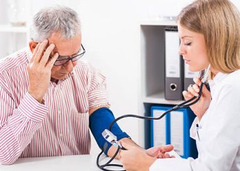 Doctor measuring blood pressure of an elderly man with a headach