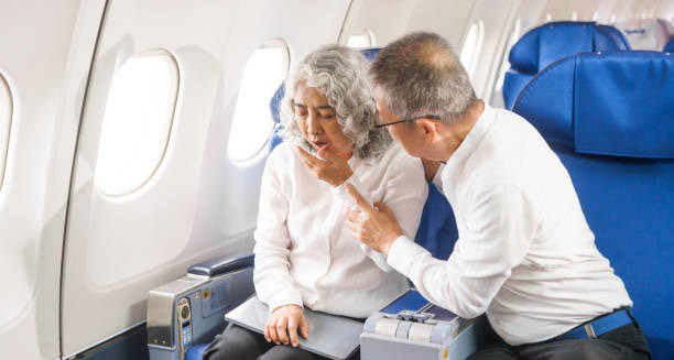 Elderly woman feeling unwell on a flight, attended by a concerned man—potential symptoms of jet lag