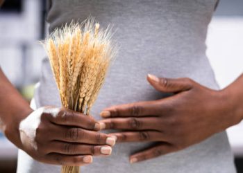 Woman holding wheat and touching stomach, symbolising food intolerance