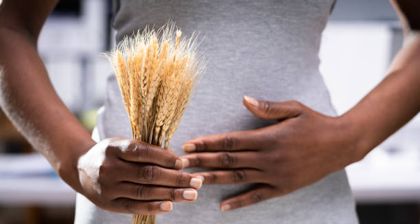 Woman holding wheat and touching stomach, symbolising food intolerance
