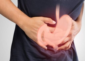 Person clutching stomach with illustrated digestive system overlay indicating stomach discomfort