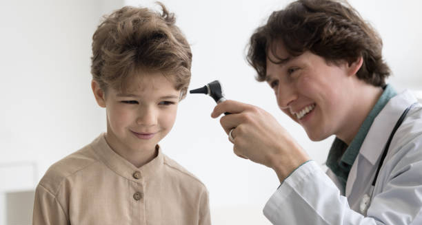 Doctor examining young boy’s ear with an otoscope