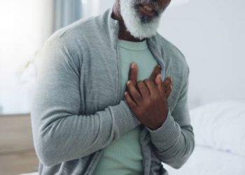 Older man clutching his chest in pain, indicating possible symptoms of heart failure