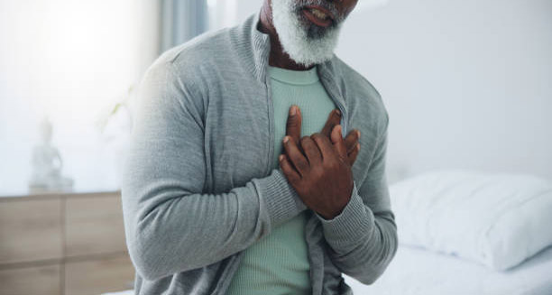 Older man clutching his chest in pain, indicating possible symptoms of heart failure