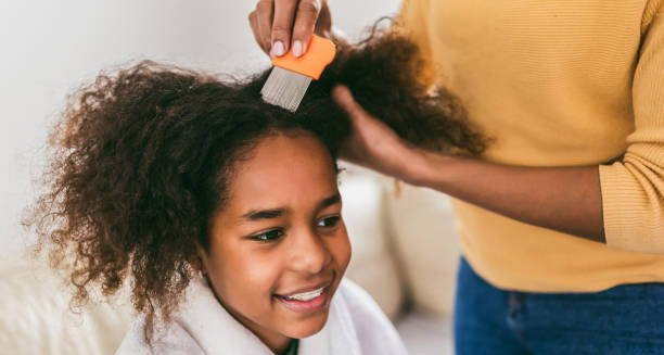 Smiling child having hair combed with a lice comb during head lice treatment