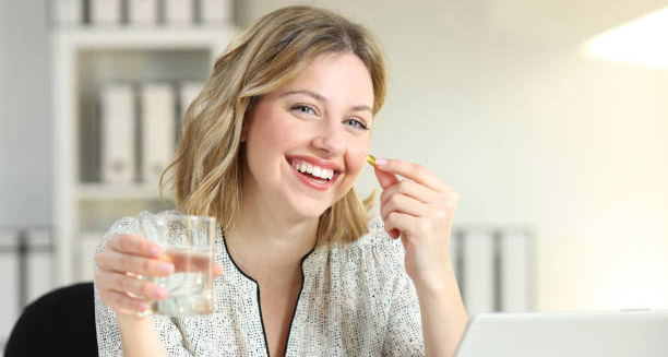 Smiling woman holding a pill and water, representing positive outlook for Hepatitis C treatment