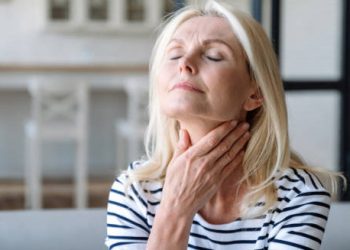 Mature woman reflecting while holding her neck, symbolising outlook for Hodgkin lymphoma