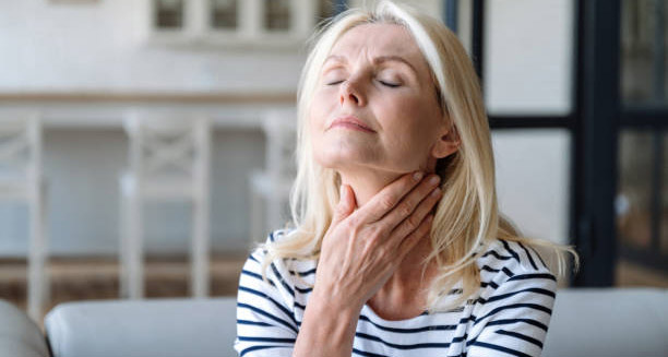 Mature woman reflecting while holding her neck, symbolising outlook for Hodgkin lymphoma