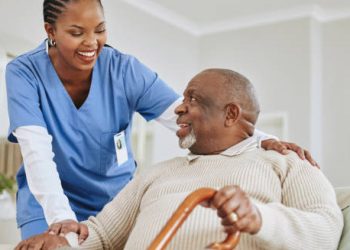 Elderly man smiling with caregiver during recovery from hookworm complications